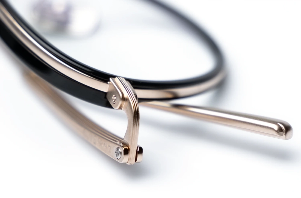Detailaufnahme einer Bada Brille mit goldenem Titanrand und schwarzer Rahmenumfassung – Kitschenberg